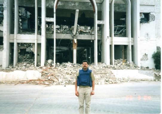 Muhammad Farhan Aslam in front of the bombed former Ba'ath Party headquarters in Basra, Iraq.