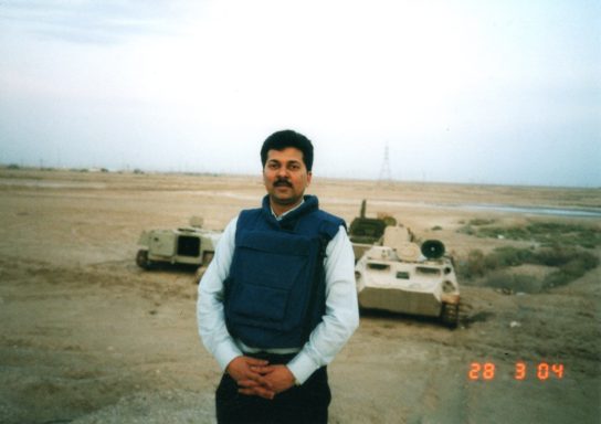 Muhammad Farhan Aslam standing near destroyed tanks outside the British base at Basra Airport, Iraq.